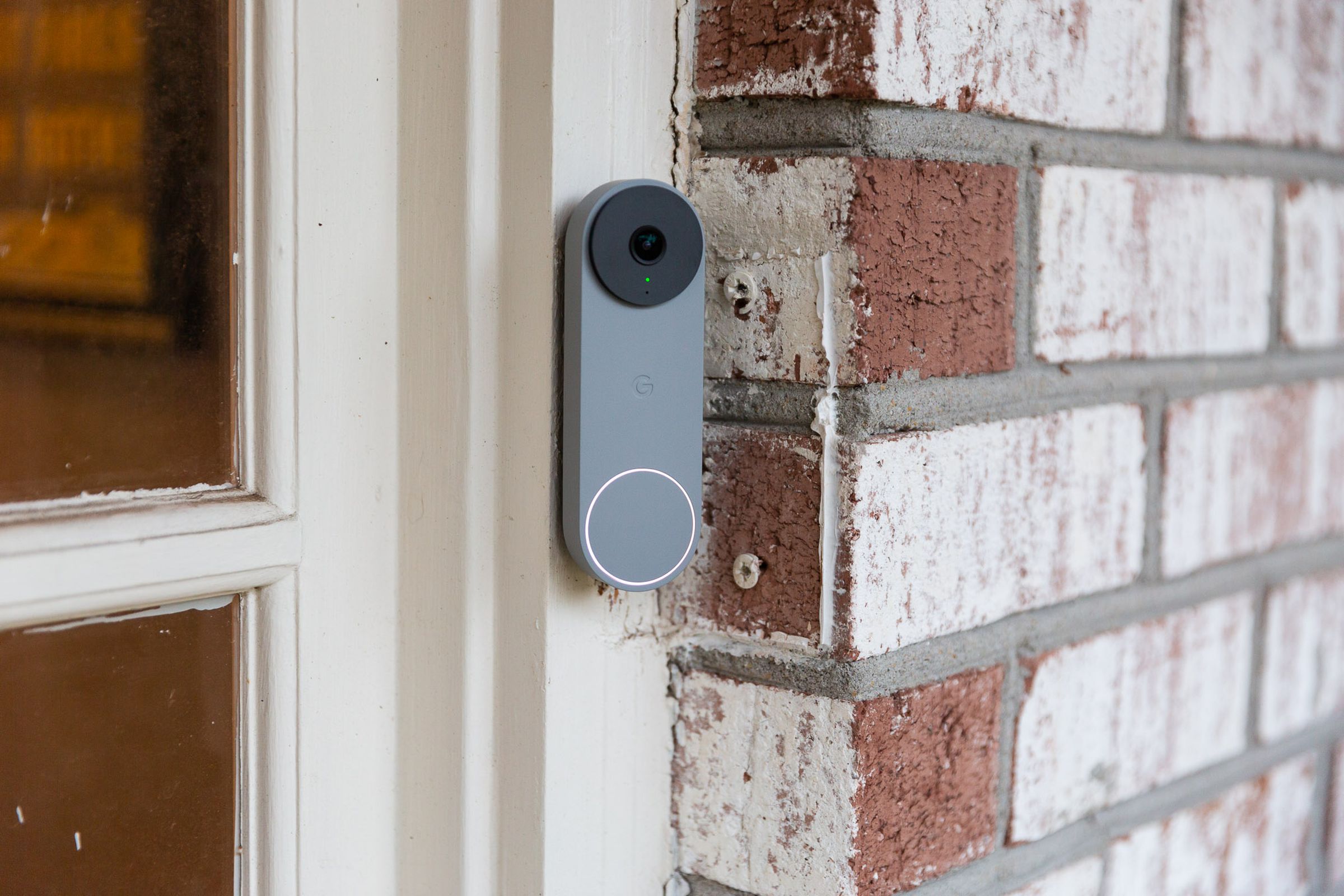 A grey Nest doorbell on a brick wall